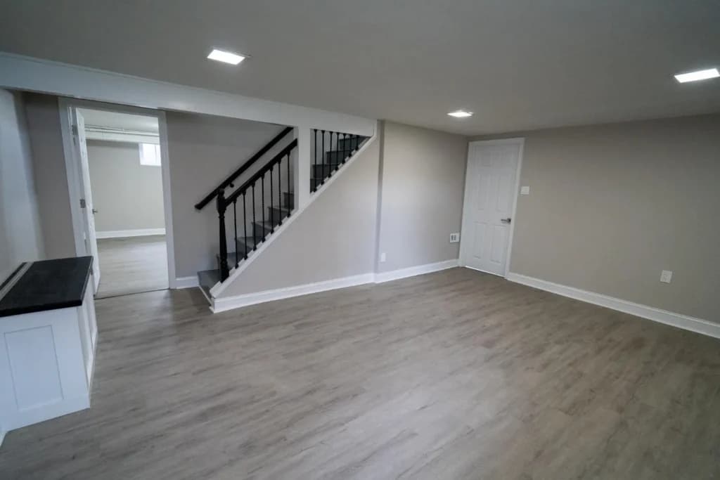 Finished basement with vinyl plank flooring, staircase with black railings, and recessed lighting in St. Catharines