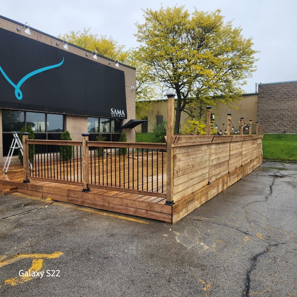 Wooden deck with railings, string lights and privacy wall for outdoor patio
