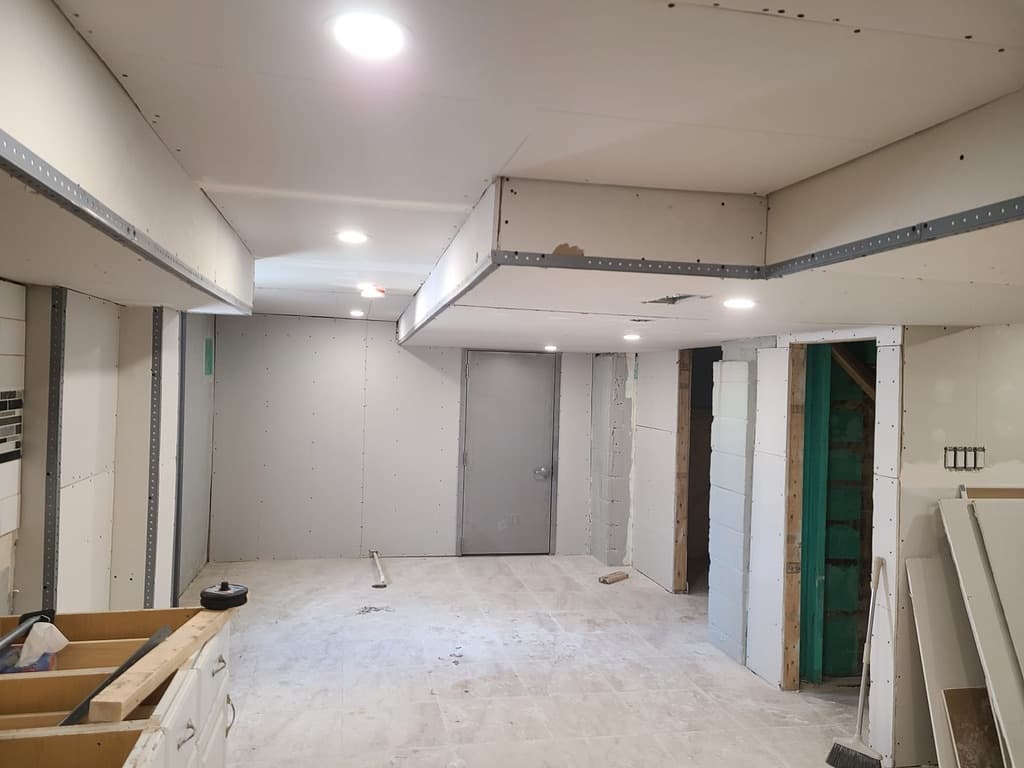 Drywall installation in progress with metal corner beads and screw patterns