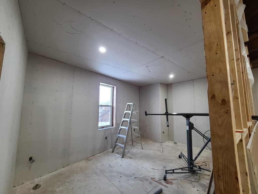 Drywall sheets installed with visible screws and metal corner bead ready for taping