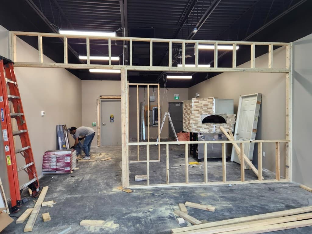 Interior framing and structural work in progress with wooden stud walls and brick-faced oven