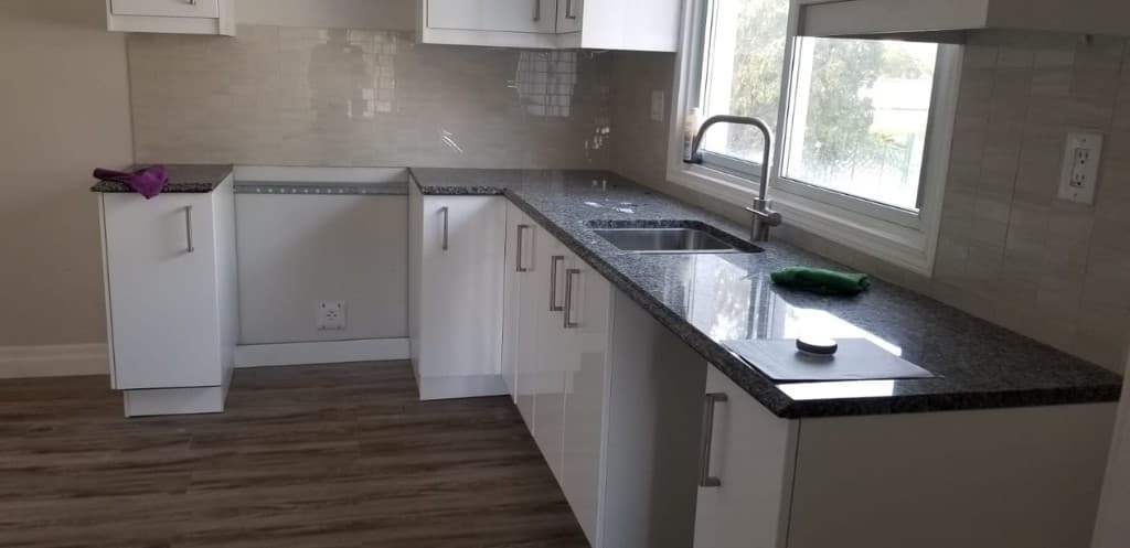 Contemporary kitchen with white cabinets, dark granite countertops and tile backsplash
