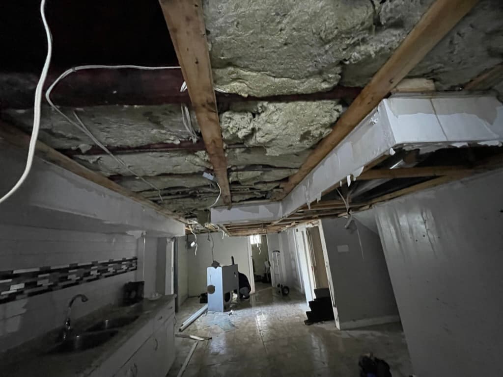 Flood-damaged Niagara basement stripped to the studs, with soaked drywall and insulation removed from the ceiling