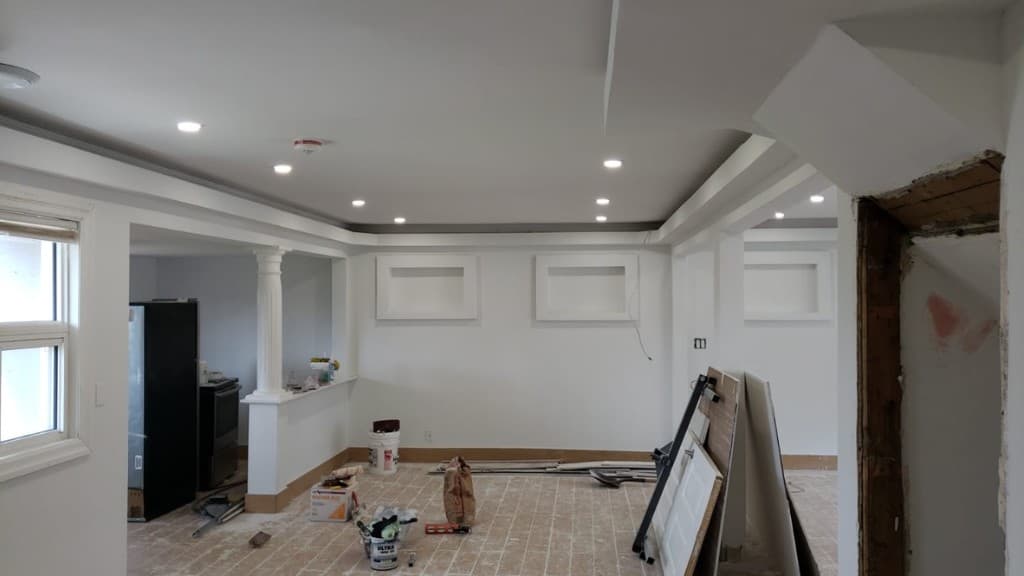 Finished basement rebuilt after water damage, with new drywall, trim, and pot lights