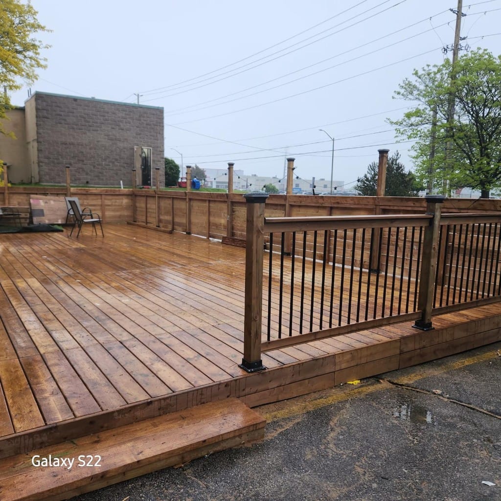 Completed wood commercial patio with privacy wall and black railing