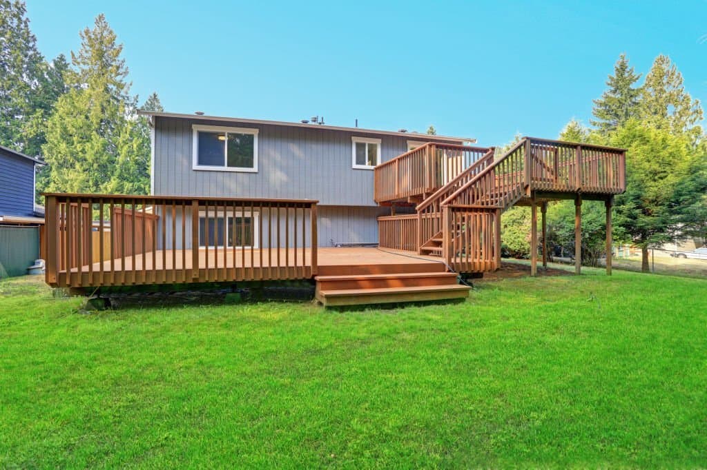 Finished multi-level backyard deck with wood railings and lawn