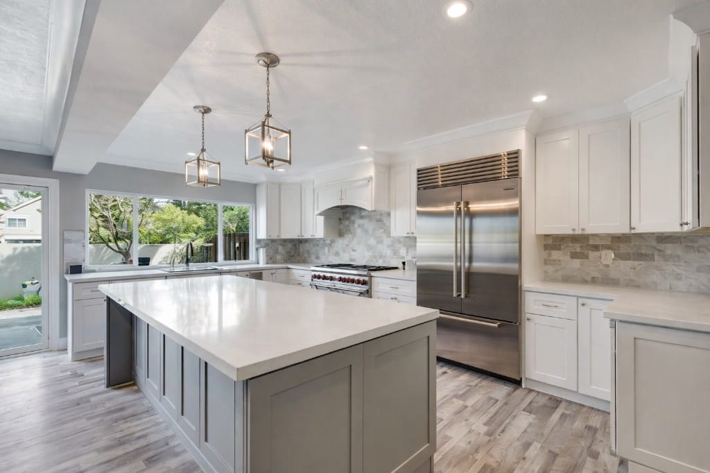 White kitchen with a grey island, stainless appliances and lantern pendant lights